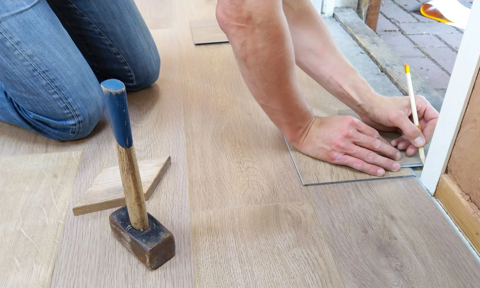 Instalador midiendo y marcando tablones de piso vinílico SPC